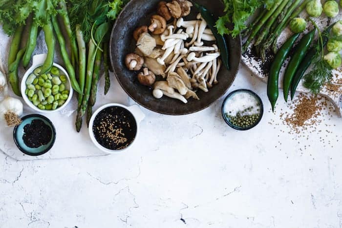 Tisch gedeckt mit Tellern voller gesunder, vegetarischer und veganer Lebensmitteln. Pilze, Sojabohnen, Gemüse
