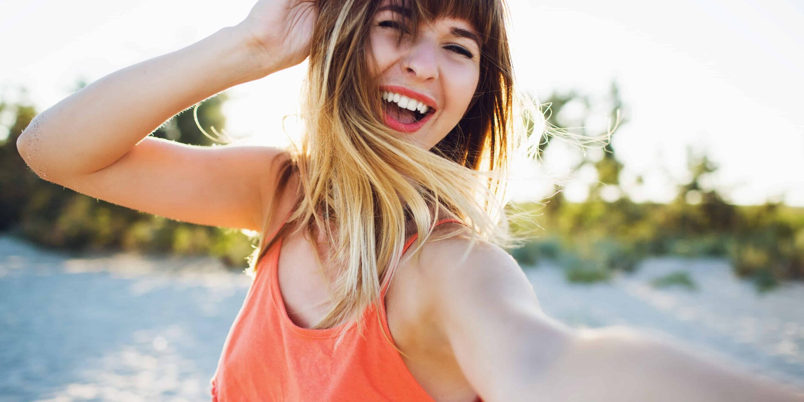 Glücklich sein Junge Frau mit orangenem Trägretkleid lacht und ist glücklich