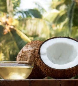 Kokosnusshälfte auf Tisch und Schale aus Glas gefüllt mit Kokosöl