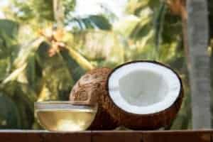 Kokosnusshälfte auf Tisch und Schale aus Glas gefüllt mit Kokosöl