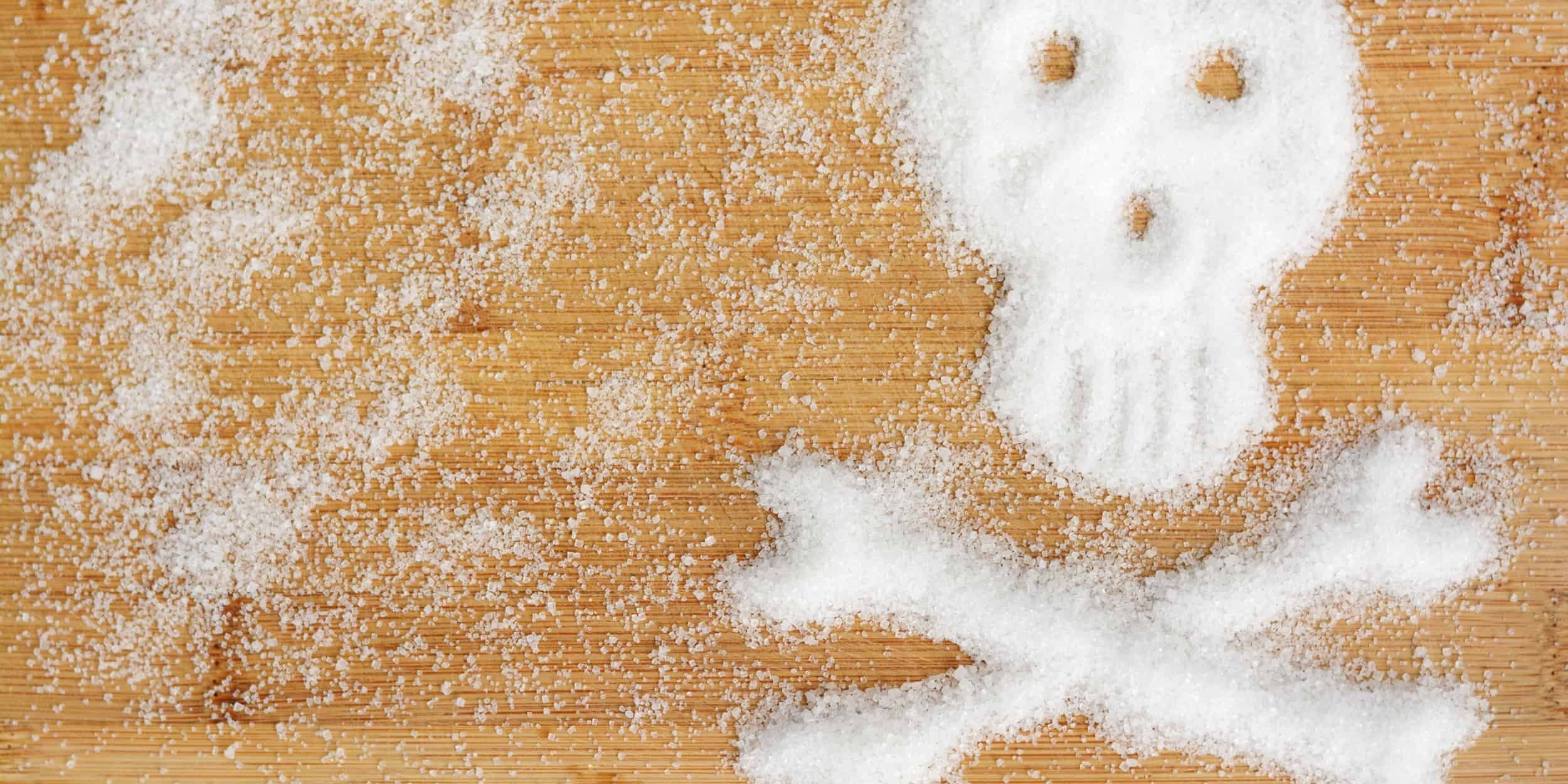 Holztisch mit Fructose Pulver in Totenkopf Form - gefährlicher Dickmacher