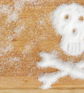 Holztisch mit Fructose Pulver in Totenkopf Form - gefährlicher Dickmacher