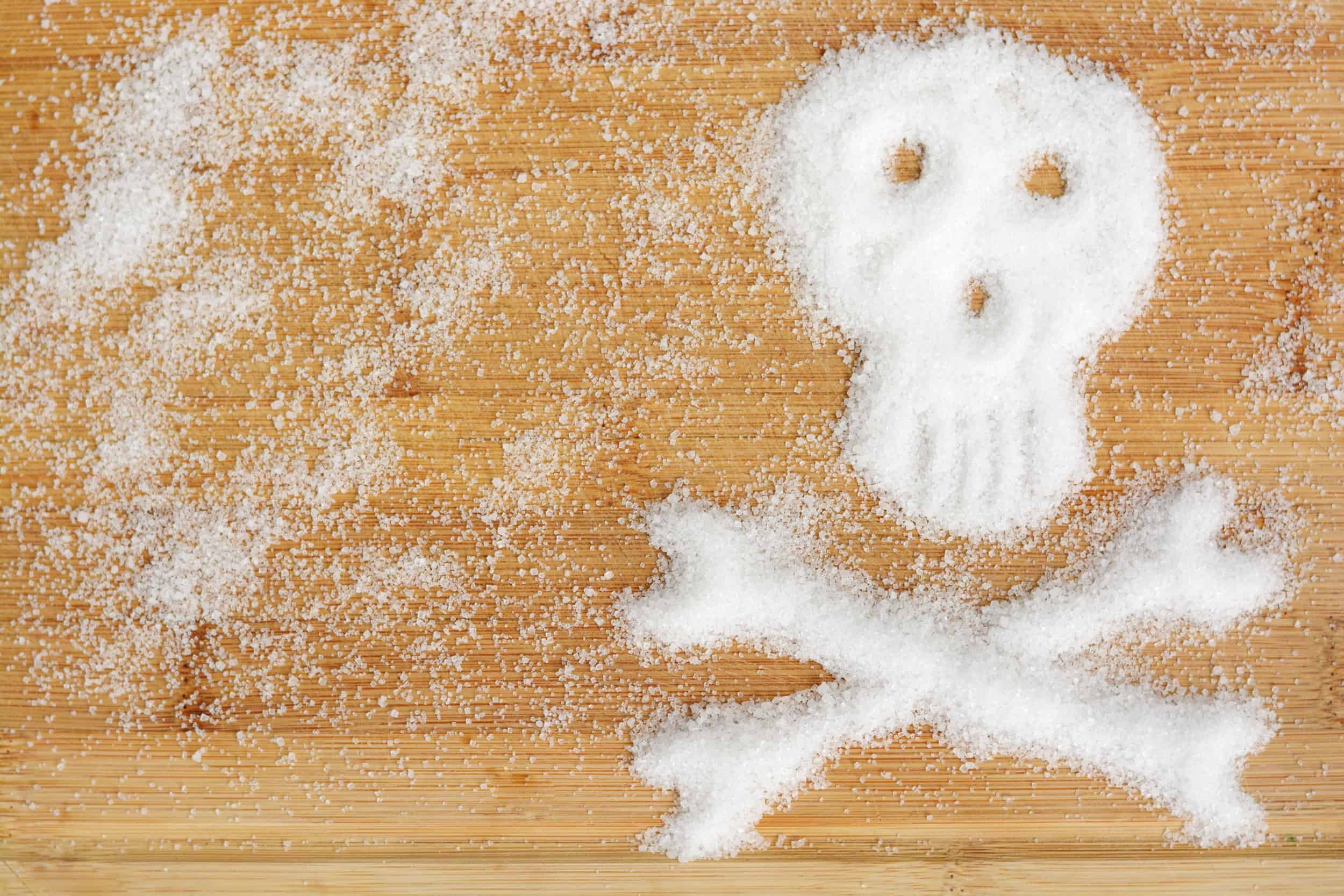 Holztisch mit Fructose Pulver in Totenkopf Form - gefährlicher Dickmacher
