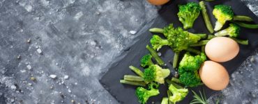 broccoli und eier auf brett dunkelgrauer tisch