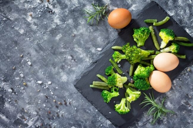broccoli und eier auf brett dunkelgrauer tisch