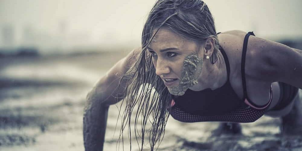 Crawling Trainierte Frau macht Crawling Fitness und krabbelt durch den Schlamm