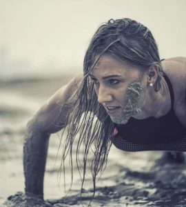 Trainierte Frau macht Crawling Fitness und krabbelt durch den Schlamm