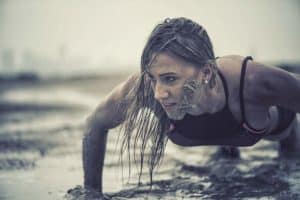 Trainierte Frau macht Crawling Fitness und krabbelt durch den Schlamm