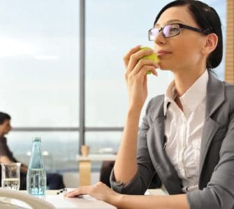 Frau isst gesund am Arbeitsplatz