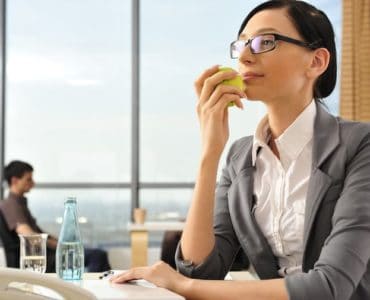 Frau isst gesund am Arbeitsplatz