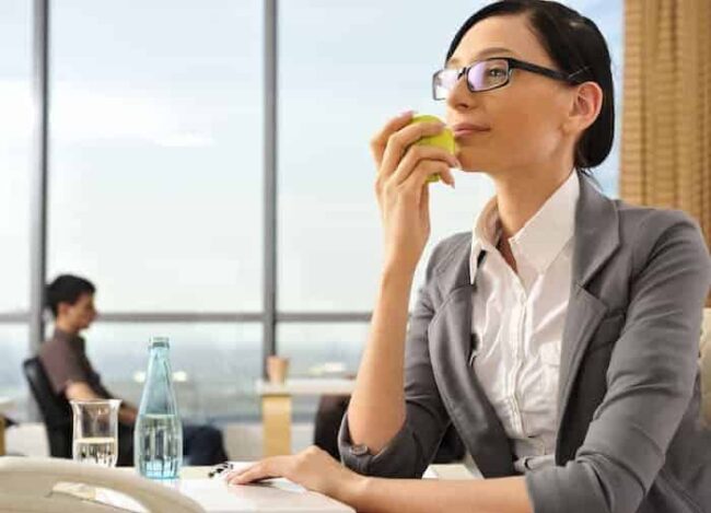 shutterstock_75673003 Frau isst gesund am Arbeitsplatz