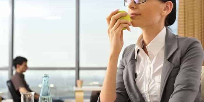 shutterstock_75673003 Frau isst gesund am Arbeitsplatz