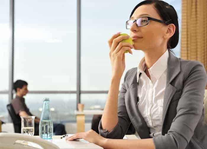 Frau isst gesund am Arbeitsplatz