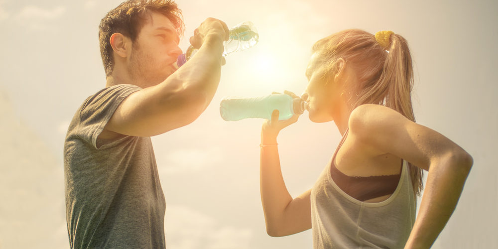 Frau und Mann stehen sich gegenüber und trinken Wasser