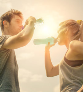 Frau und Mann stehen sich gegenüber und trinken Wasser