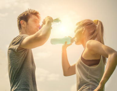 Frau und Mann stehen sich gegenüber und trinken Wasser