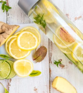Eine Glasflasche mit frischem Ingwerwasser und Zitronenscheiben