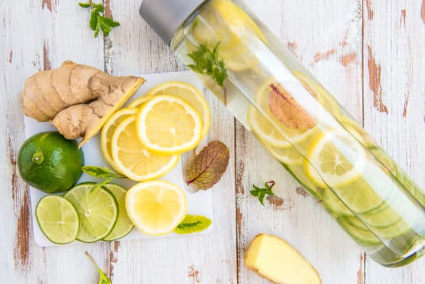 Eine Glasflasche mit frischem Ingwerwasser und Zitronenscheiben