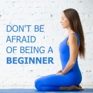 Junge Frau in blauem Sporttrikot macht Yoga neben ihr ein Schriftzug: Keine Angst ein Anfänger zu sein