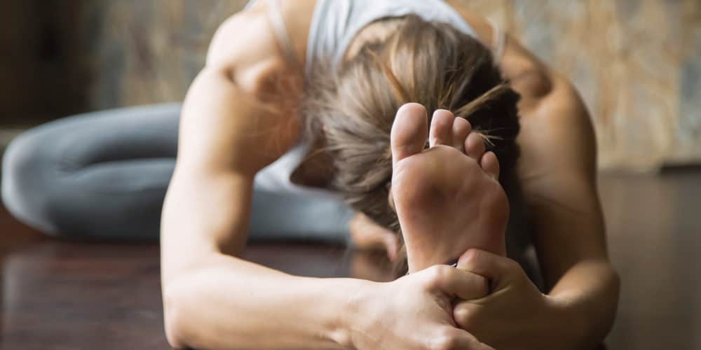 Yoga für Einsteiger Junge Frau auf Yogamatte macht eine Vorbeuge