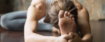 Junge Frau auf Yogamatte macht eine Vorbeuge