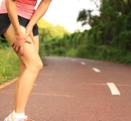 Übersäuerte Sportlerin hält sich den Oberschenkel