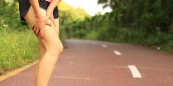 Übersäuerung Sportlerin Übersäuerte Sportlerin hält sich den Oberschenkel